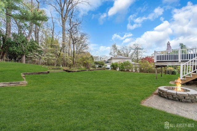 view of yard featuring a wooden deck, a fire pit, and stairway