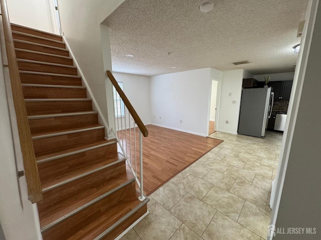 stairs featuring hardwood / wood-style flooring and a textured ceiling