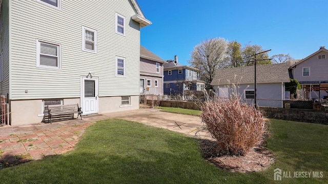 back of property featuring a lawn, a patio area, fence, and a residential view