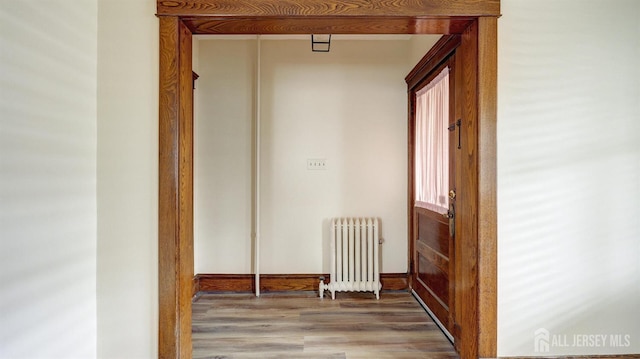 corridor with wood finished floors and radiator