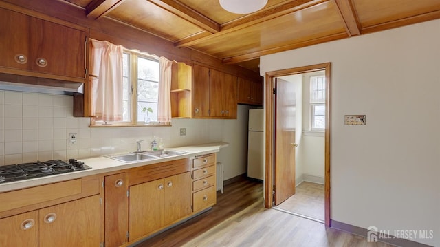 kitchen with a sink, light countertops, freestanding refrigerator, and gas stovetop