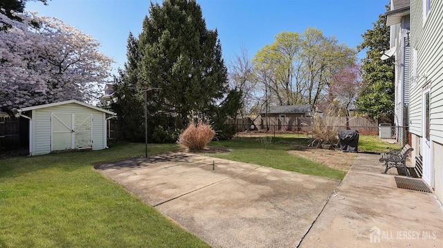 view of yard with a patio, fence, an outbuilding, and a storage unit