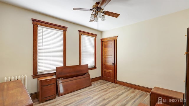 office space with a ceiling fan, baseboards, radiator heating unit, and light wood-type flooring