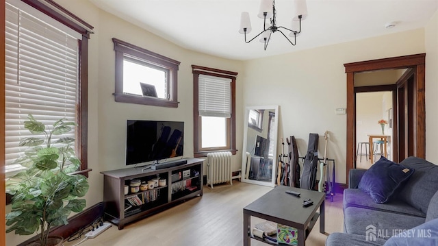 living area featuring an inviting chandelier, plenty of natural light, radiator heating unit, and light wood-type flooring