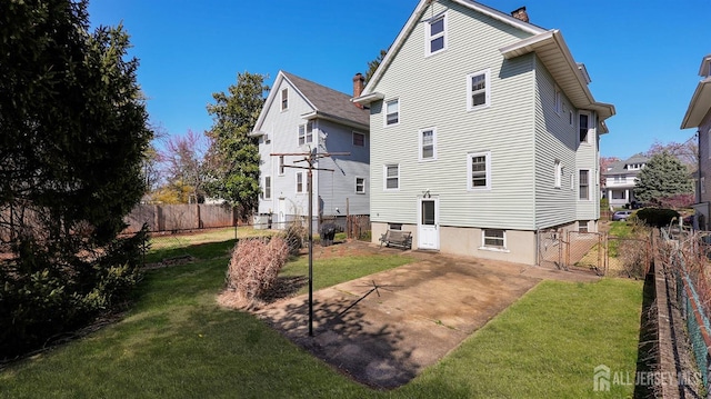 back of house featuring a lawn, a gate, a chimney, and a fenced backyard