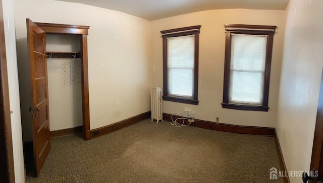 unfurnished bedroom featuring radiator, baseboards, and carpet floors