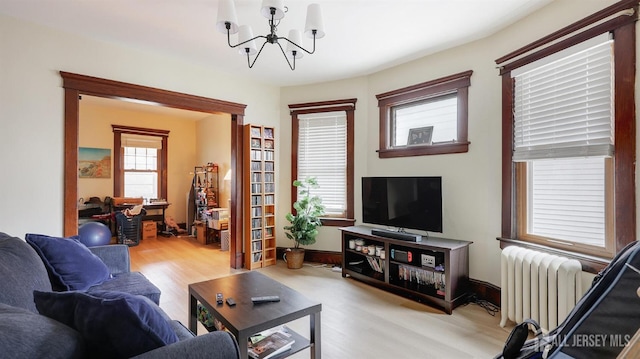 living area with radiator heating unit, wood finished floors, and a chandelier