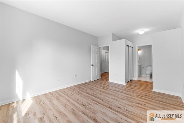 unfurnished bedroom with ensuite bath, baseboards, and light wood-style floors