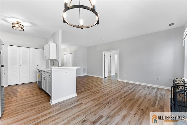 kitchen featuring light wood-type flooring, visible vents, baseboards, and light countertops