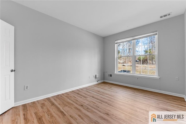 unfurnished room featuring light wood-style floors, visible vents, and baseboards