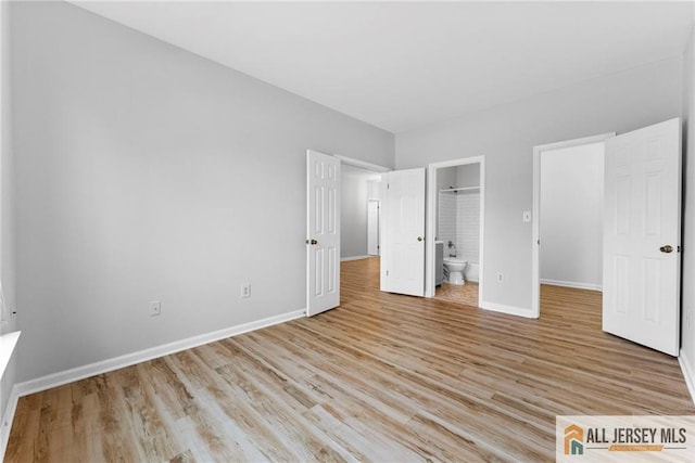 unfurnished bedroom featuring ensuite bath, light wood-type flooring, and baseboards