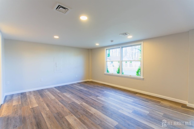 spare room with recessed lighting, wood finished floors, visible vents, and baseboards