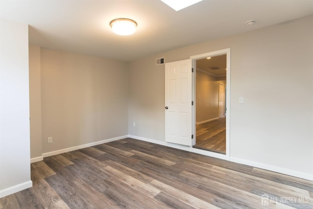 unfurnished room with wood finished floors, visible vents, and baseboards