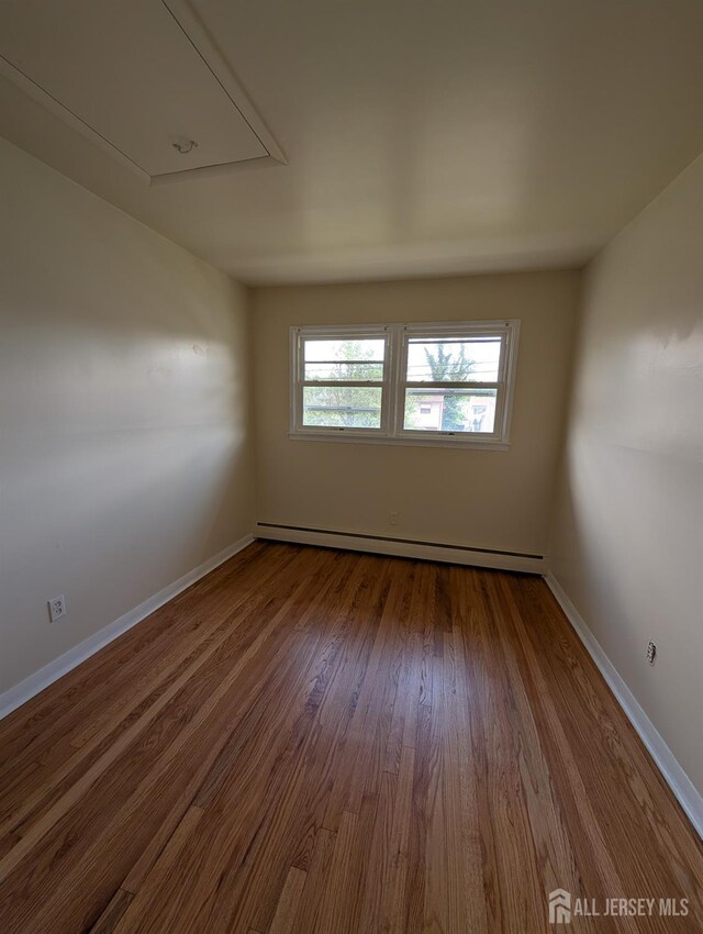 25 Predmore Ave, Colonia, NJ 07067 - empty room featuring baseboard heating, attic access, and dark wood finished floors