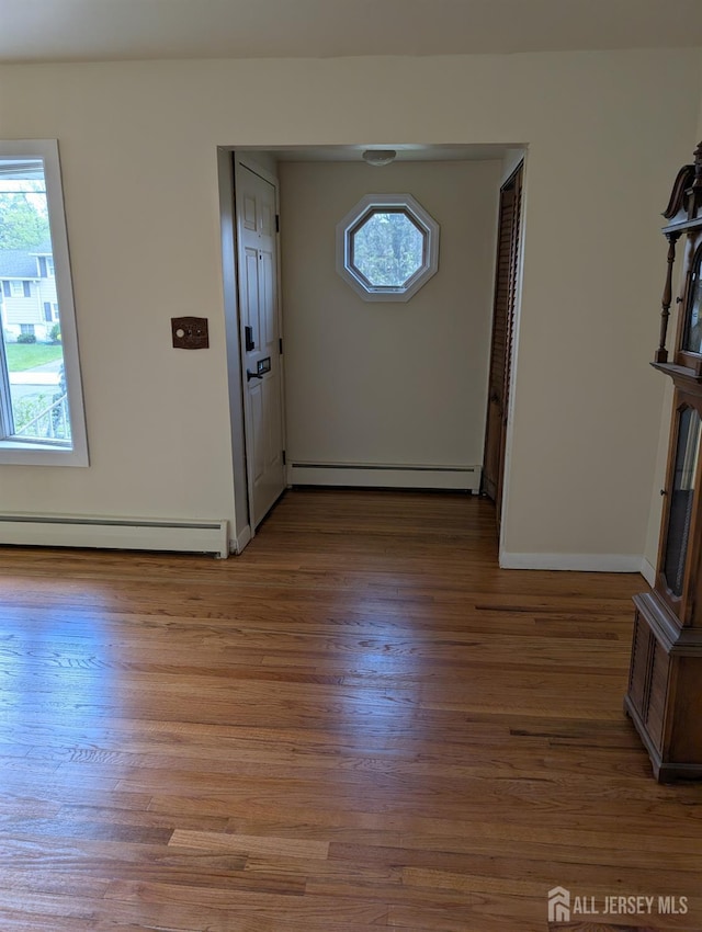 foyer with a baseboard heating unit, wood finished floors, and baseboards