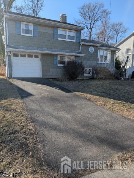view of front of home featuring a chimney, asphalt driveway, and an attached garage