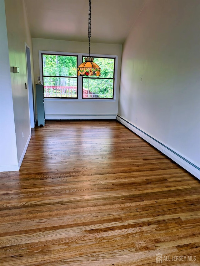 unfurnished dining area featuring wood finished floors, baseboards, a baseboard heating unit, and baseboard heating