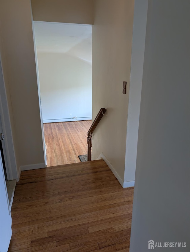 hall featuring an upstairs landing, wood finished floors, baseboards, and lofted ceiling