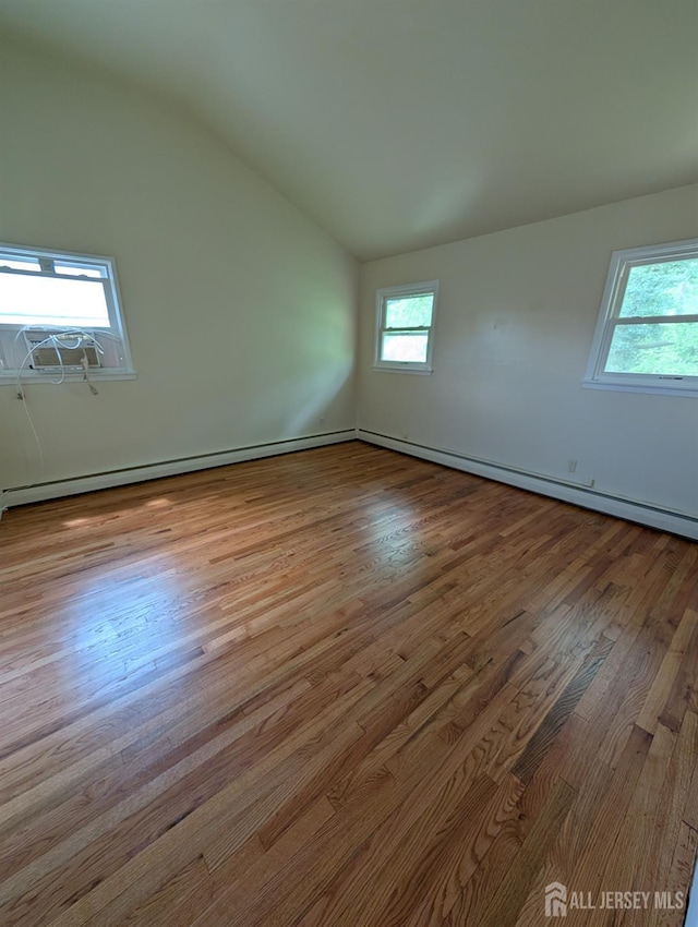 unfurnished room with vaulted ceiling, wood finished floors, and baseboard heating