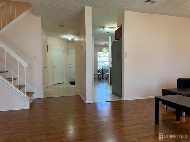 interior space featuring visible vents, stairway, a textured ceiling, wood finished floors, and baseboards