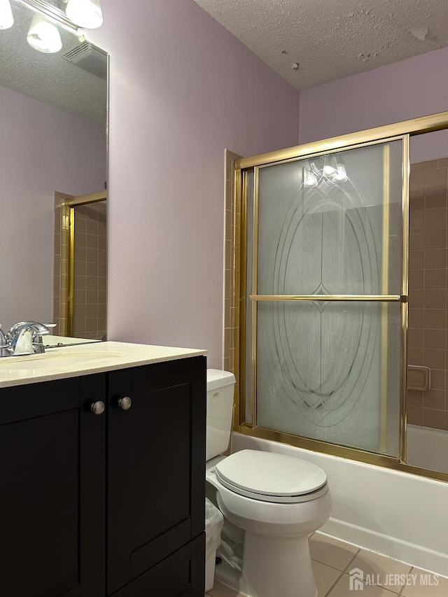 full bath with a textured ceiling, bath / shower combo with glass door, tile patterned flooring, and vanity