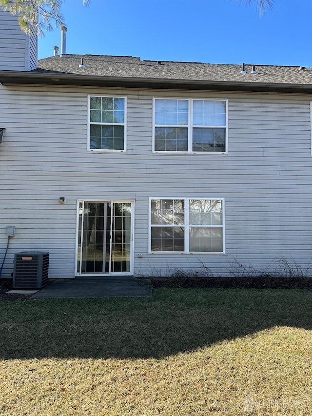 rear view of house featuring central air condition unit, a lawn, and a patio