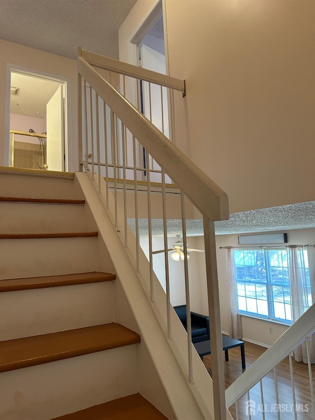 staircase featuring a textured ceiling and wood finished floors