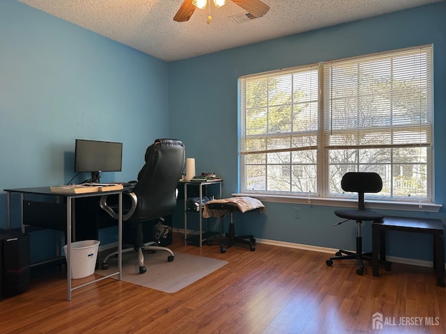 office with baseboards, visible vents, ceiling fan, wood finished floors, and a textured ceiling