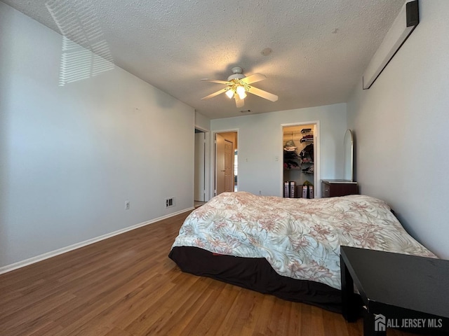 bedroom with visible vents, dark wood-type flooring, a walk in closet, a textured ceiling, and a closet