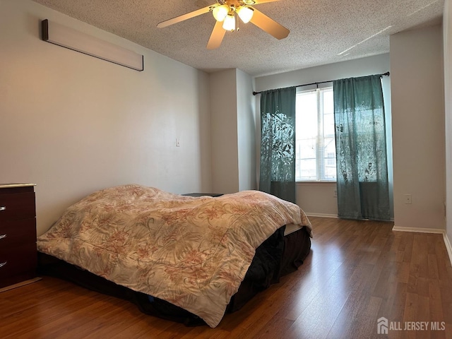 bedroom featuring a textured ceiling, wood finished floors, a ceiling fan, and baseboards