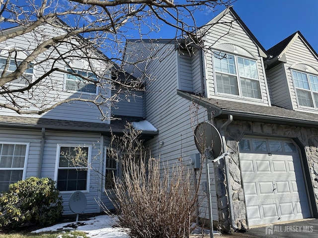 view of side of property with a garage and roof with shingles