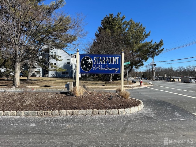 community / neighborhood sign featuring uncovered parking