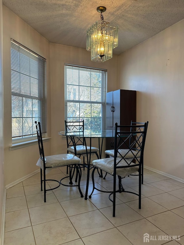 dining space featuring a chandelier, a textured ceiling, and light tile patterned flooring