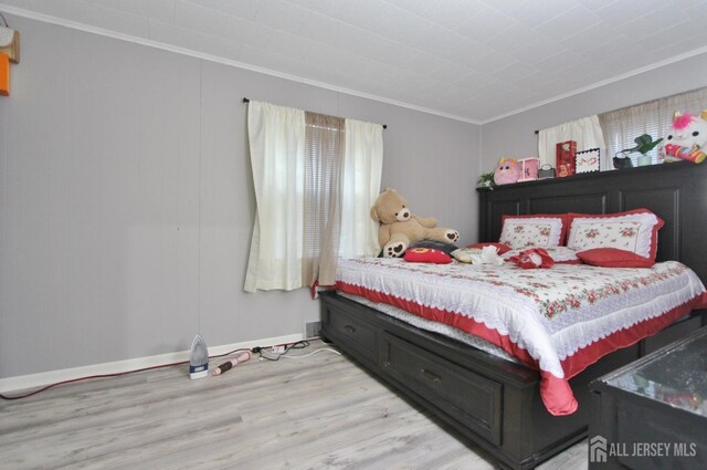 bedroom with crown molding and light hardwood / wood-style floors