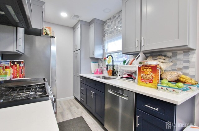 kitchen featuring light hardwood / wood-style floors, extractor fan, stainless steel appliances, decorative backsplash, and sink