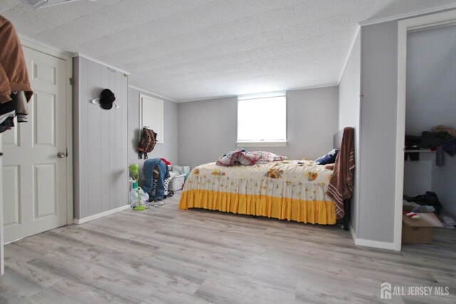 bedroom featuring light wood-type flooring, wood walls, and ornamental molding