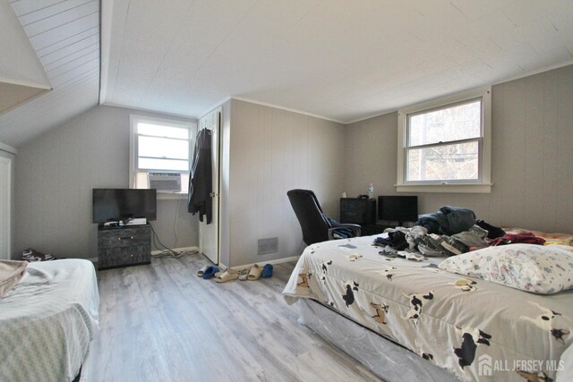 bedroom featuring light wood-type flooring, vaulted ceiling, multiple windows, and cooling unit