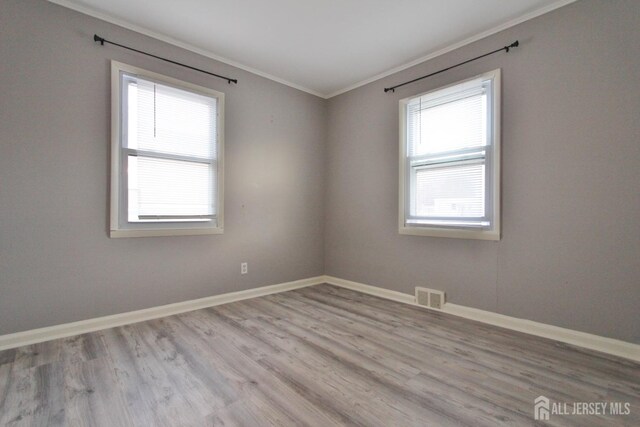 spare room featuring crown molding and light hardwood / wood-style flooring