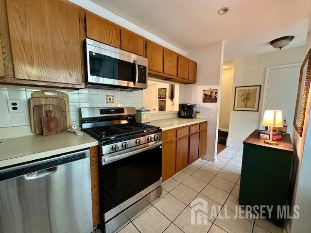 271 Constitution Cir, North Brunswick, NJ 08902 - kitchen featuring stainless steel appliances, brown cabinets, light countertops, and tasteful backsplash