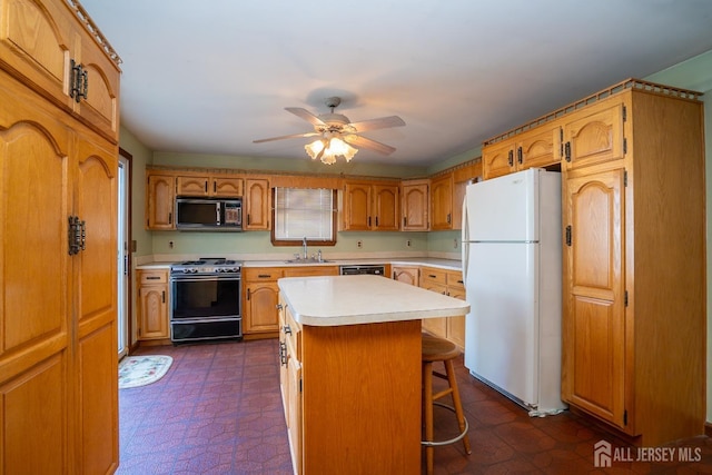 kitchen with sink, a breakfast bar area, a center island, ceiling fan, and black appliances