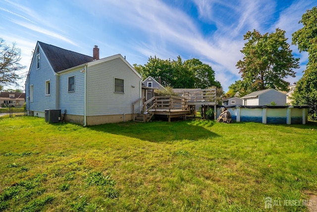 back of property with a lawn, central air condition unit, and a swimming pool side deck