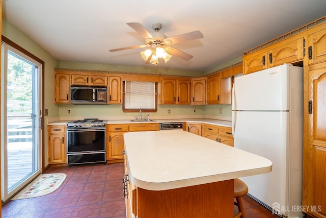 kitchen featuring a kitchen island, range with gas stovetop, sink, a kitchen bar, and white fridge