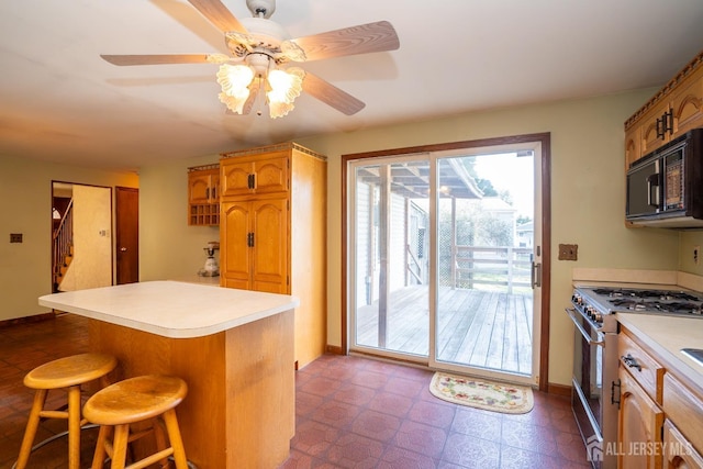 kitchen featuring ceiling fan, a breakfast bar, and high end stove