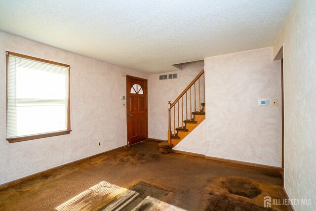 carpeted foyer entrance featuring a textured ceiling