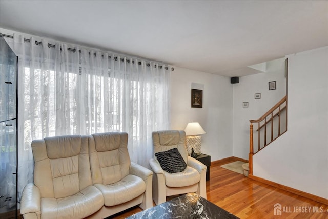 living room featuring plenty of natural light, wood finished floors, stairway, and baseboards