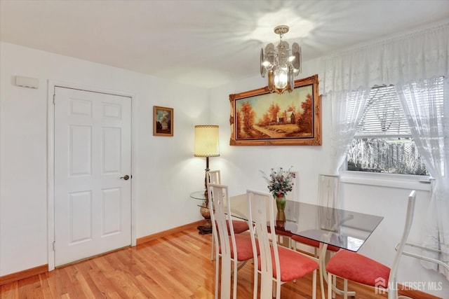 dining area featuring a chandelier, light wood-style flooring, and baseboards