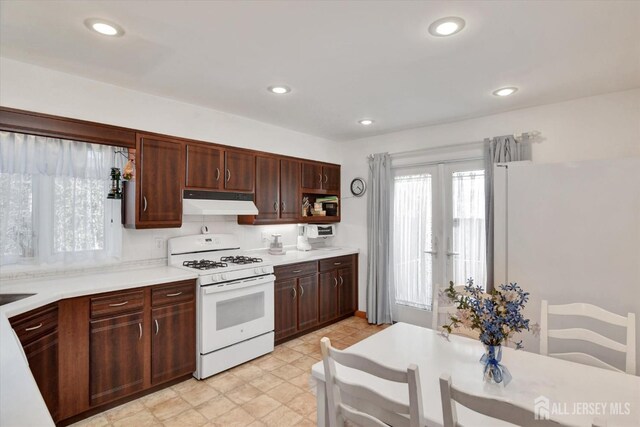 kitchen featuring white appliances, under cabinet range hood, light countertops, open shelves, and recessed lighting
