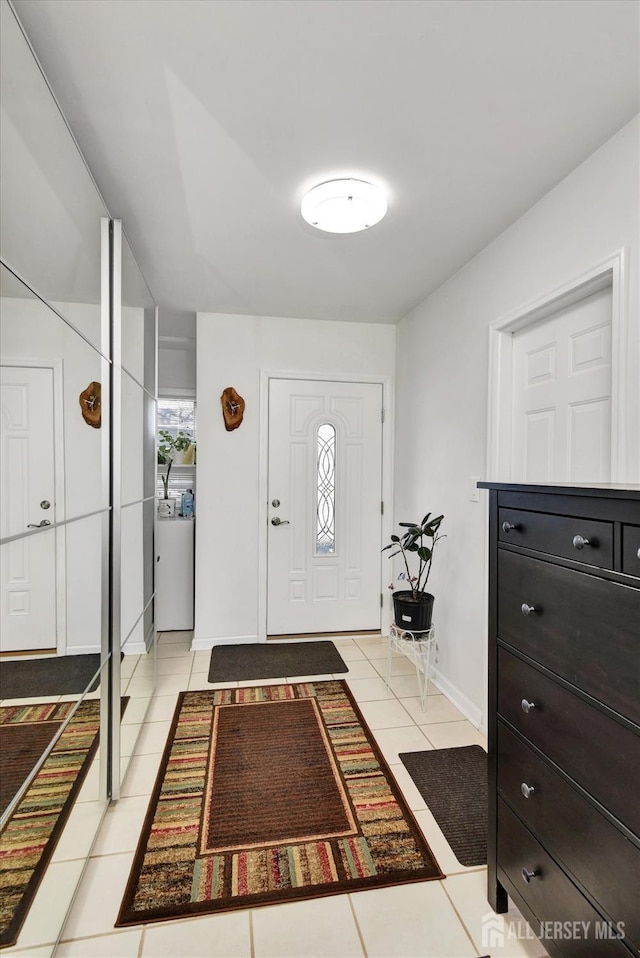 foyer entrance featuring light tile patterned flooring and baseboards
