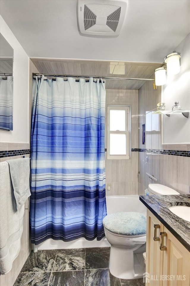 full bathroom featuring tile walls, toilet, vanity, and shower / tub combo with curtain