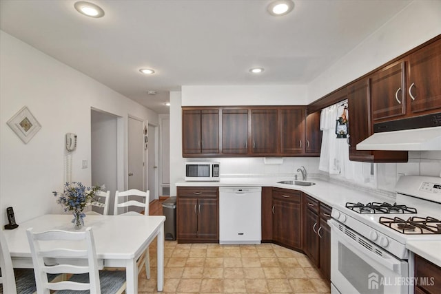 kitchen with white appliances, under cabinet range hood, a sink, light countertops, and recessed lighting